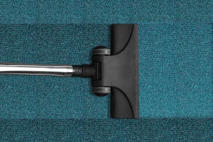 a small vacuum cleaner head cleaning a blue carpet