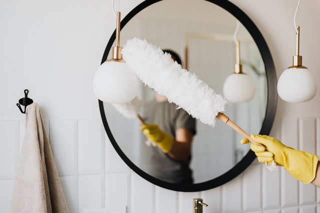 a long wand duster dusting a mirror in a bathroom