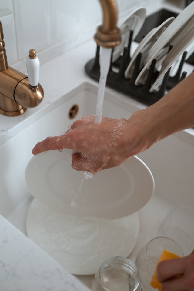 washing dishes by hand in a white sink