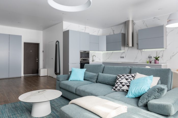 a clean and organized couch next to a kitchen