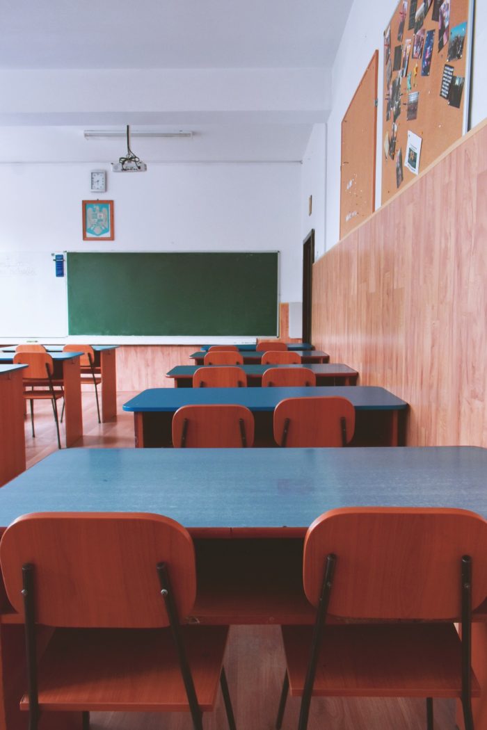 desks and chairs in a classroom with a green chalkboard