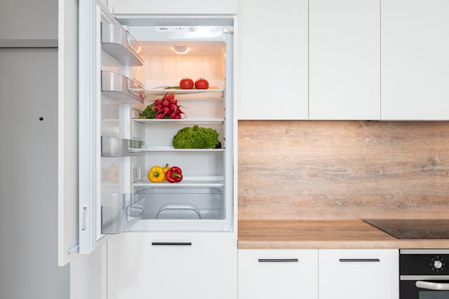 an open and very clean refrigerator with vegetables inside of it