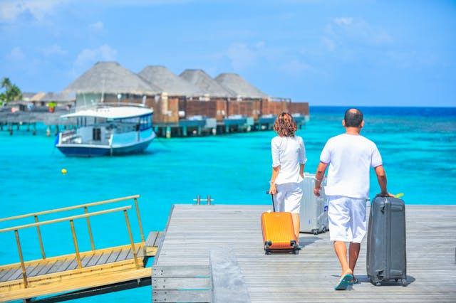 two people with suitcases in a tropical sea environment